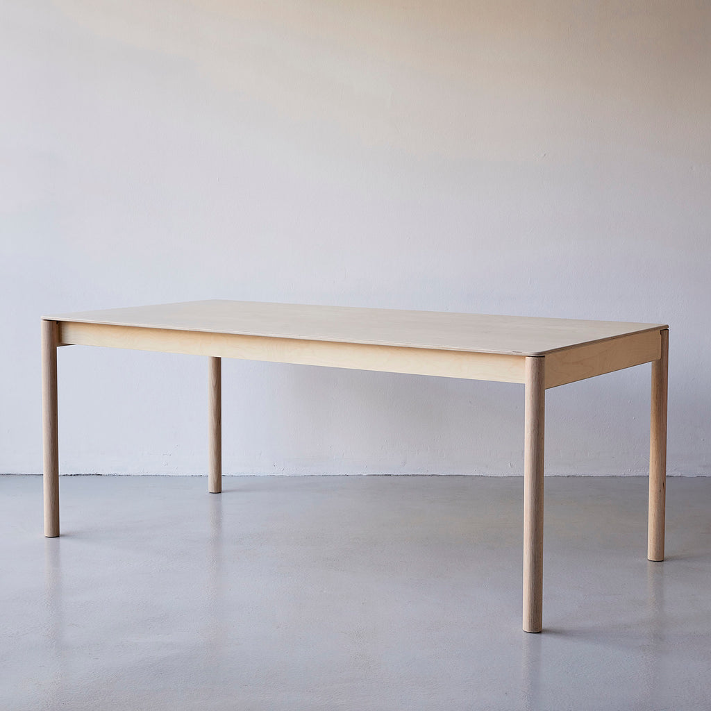 Side View of a Minimalist Natural Coloured Wooden Dining Table in a White Painted Room