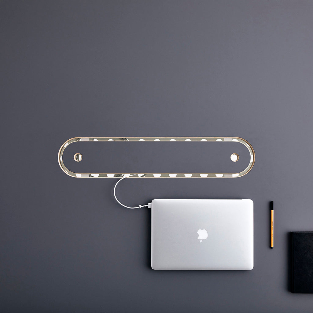 Top View of a Macbook Charging Through the Centre Cable Management Cut-out of a Gray Coloured Surface