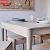 Side View of a Minimalist Natural Coloured Wooden Dining Table and Chairs with Tablewares on Top