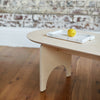 Side View of a Natural Coloured Oval Shaped Plywood Coffee Table with Lemon on a Tray