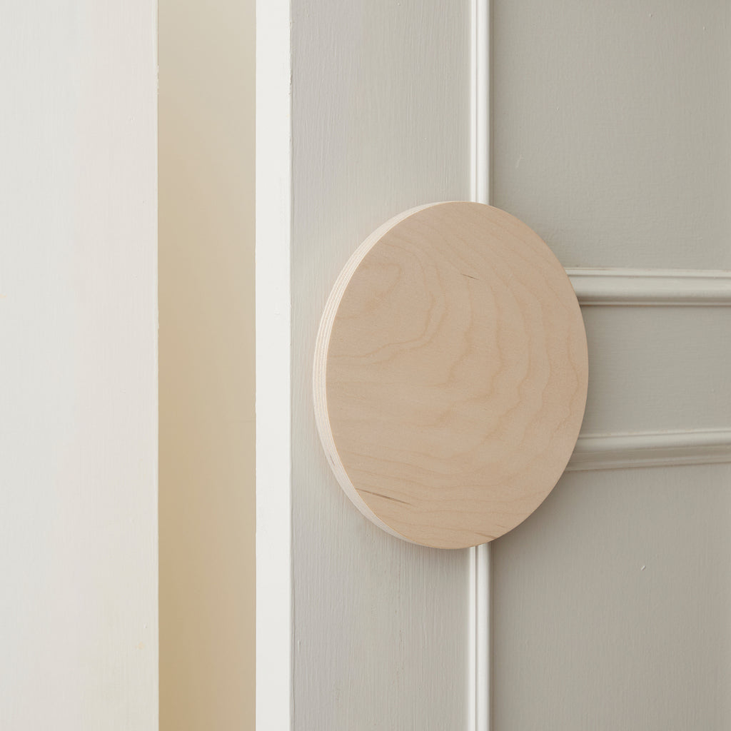 Slighly Opened White Coloured Cabinet Door with a Large Round Raw Timber Handle 
