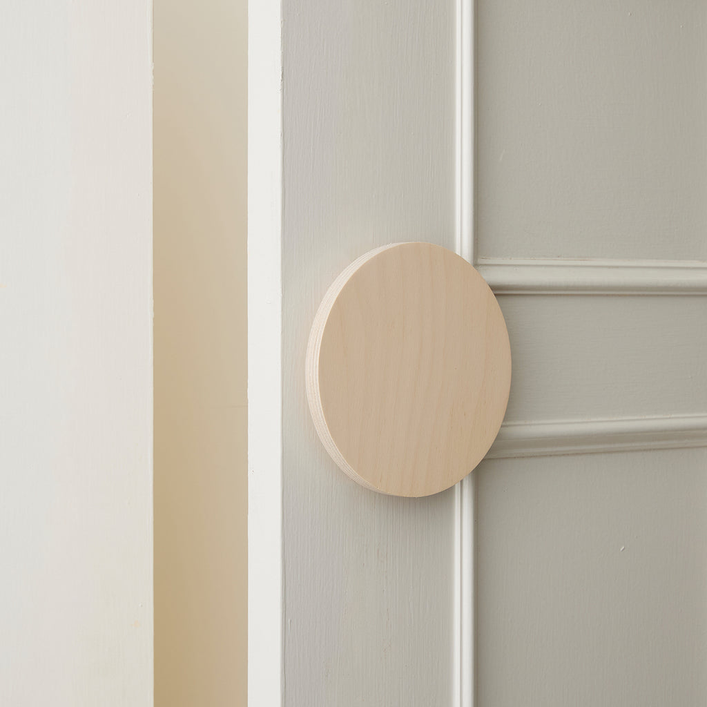 Slighly Opened White Coloured Cabinet Door with a Round Raw Timber Handle 