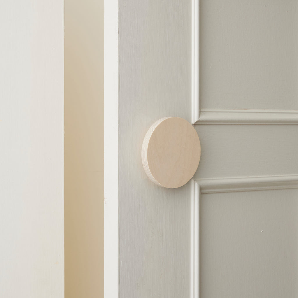 Slighly Opened White Coloured Cabinet Door with a Small Round Raw Timber Handle 