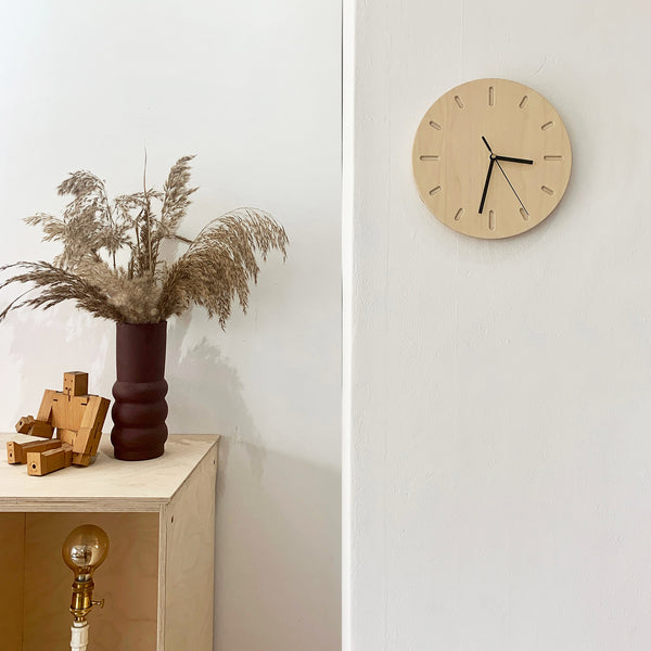 Round timber plywood wall clock with black handles on the wall